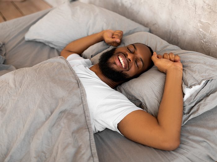 Sleep hygiene checklist - man sleeping in bed happy