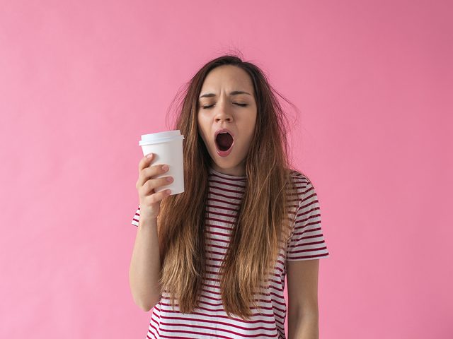 How to stay awake - yawning woman holding coffee cup