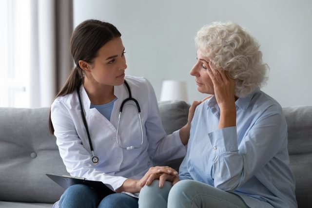 Causes of shingles - Supportive female nurse visit old grandmother patient at home