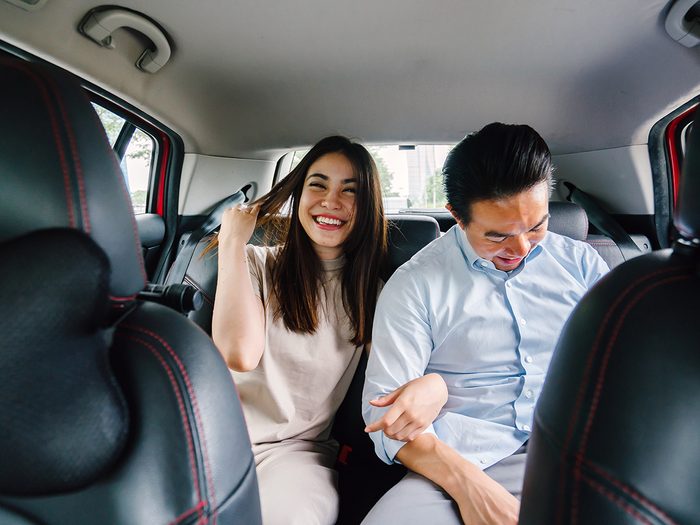 Young couple ride sharing in Uber back seat