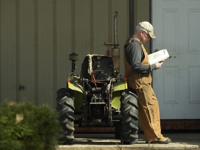 Candid photography - Man reading beside tractor
