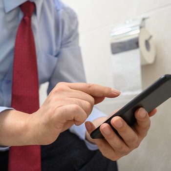 Man using phone while on toilet