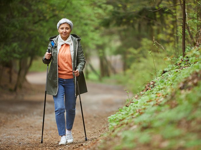 Senior woman walking along wooded trail