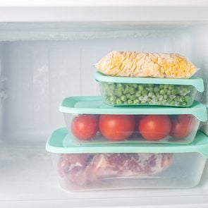 This is why there isn't a light in your freezer - Frozen vegetables and meat in blue plastic containers. Frozen corn, peas, tomatoes, meat. Cold freezer