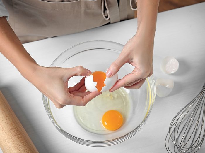Woman cracking eggs into bowl