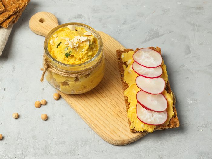 hummus, chickpea paste, with garlic, oil, tahini, spices. Vegetarian dish, perfect for sandwiches, snacks. Can of hummus and radish sandwich, close-up, selective focus