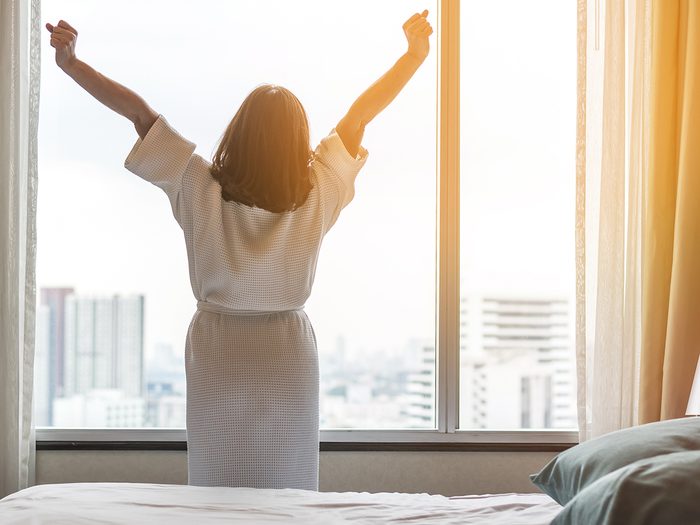 How to get a good night's sleep - woman waking up in hotel room