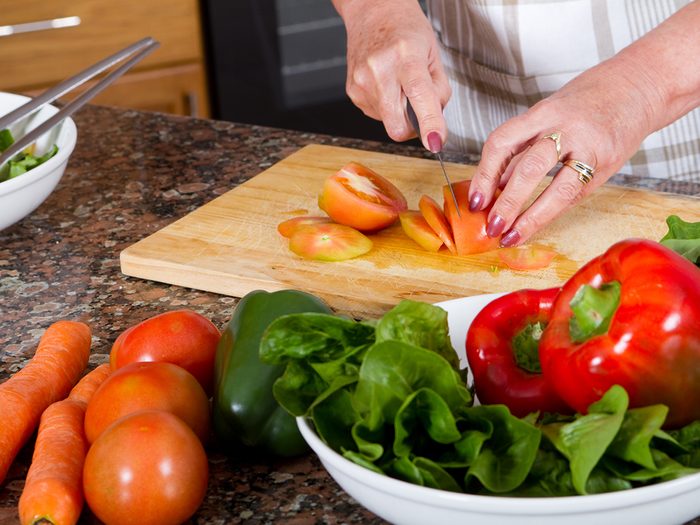 Mature woman hands slicing vegetables
