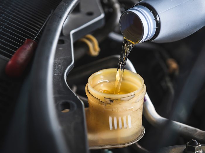 things you should never do to your car - Auto mechanic filling DOT 4 brake fluid in brake fluid reservoir