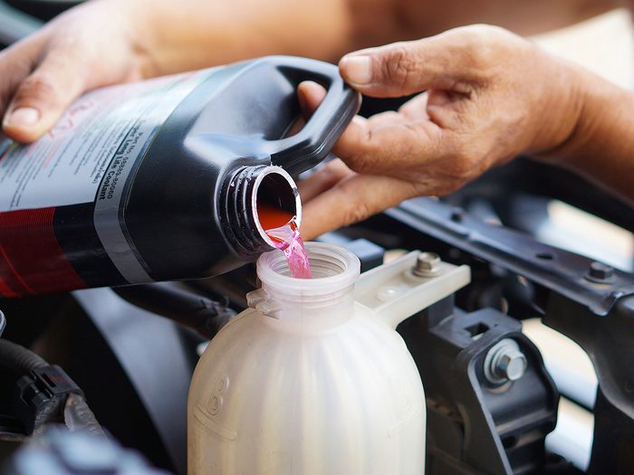things you should never do to your car - male hand filling car cooling system with coolant