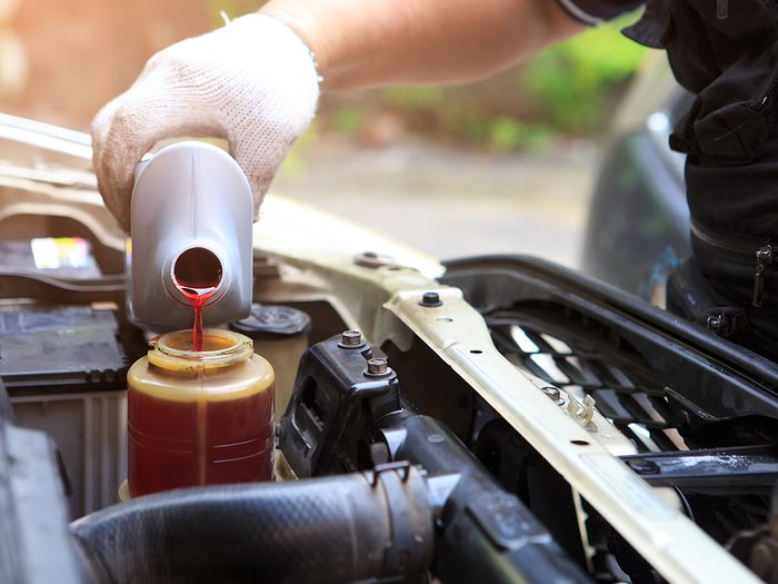 things you should never do to your car - Male hand filling car power steering fluid