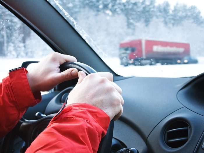 Driving car in winter - hands on steering wheel