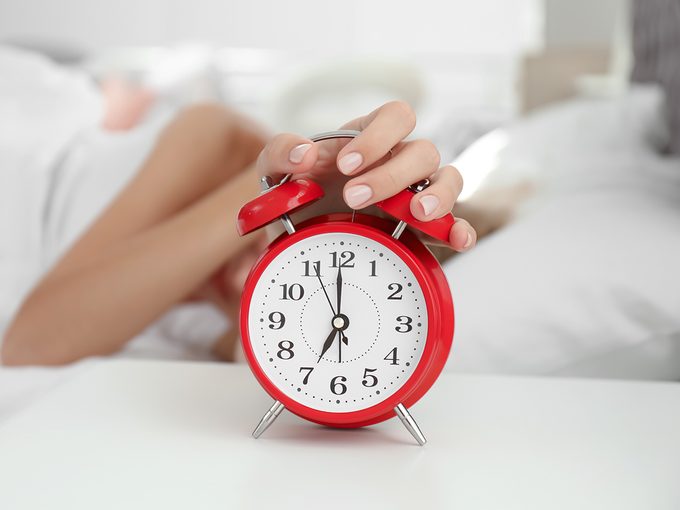 How to fix your sleep schedule - woman hitting alarm clock