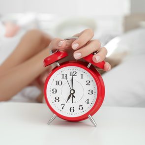 How to fix your sleep schedule - woman hitting alarm clock
