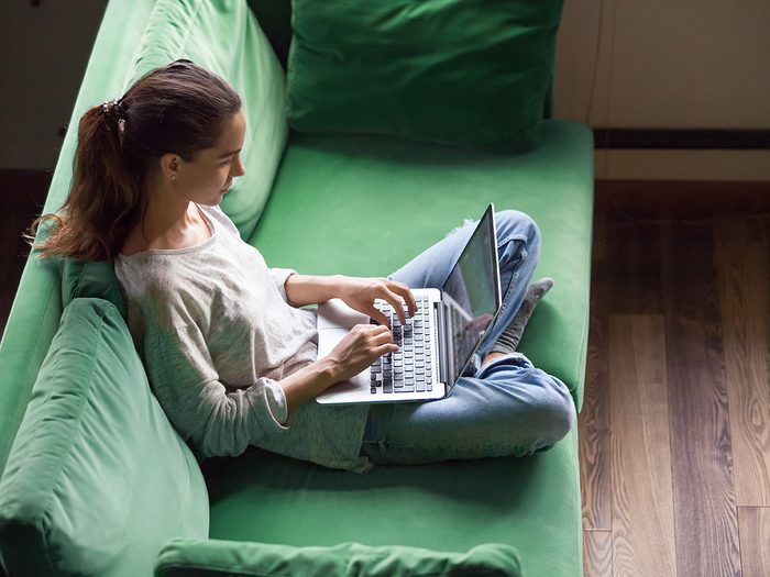how to socialize in a pandemic - Relaxed woman using laptop sitting on sofa