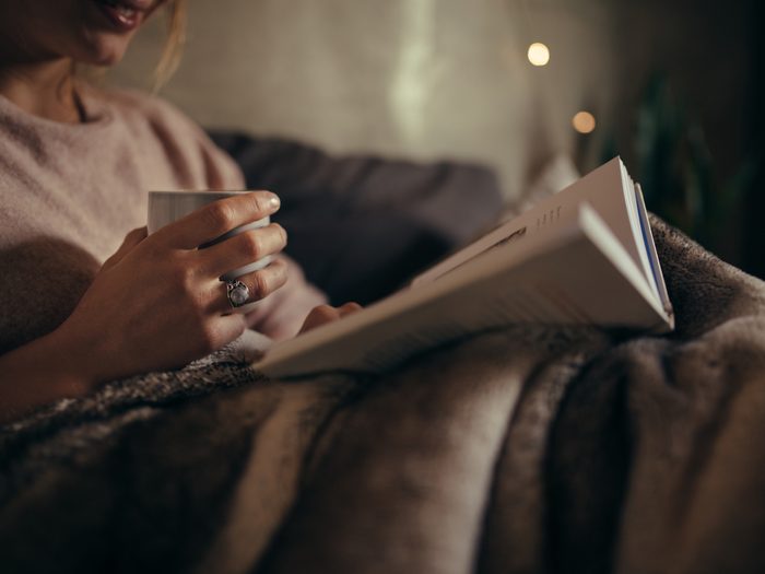 Woman reading book in bed at night