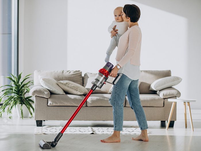 Vacuuming mistakes - woman with vacuum holding baby