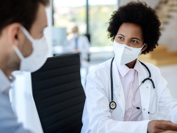 When to see your doctor - doctor communicating with a patient while wearing protective face mask during medical appointment