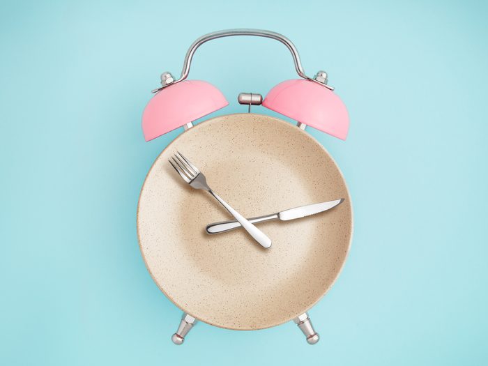 A clock with a plate face and a fork and knife for hands.