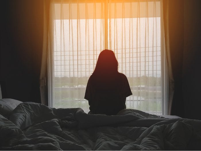 How To Fight Seasonal Affective Disorder - silhouette of woman sitting on the bed beside the windows with sunlight in the morning