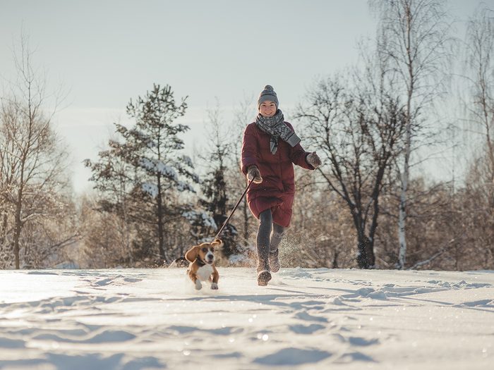 Lack of exercise symptoms - woman walking dog in winter