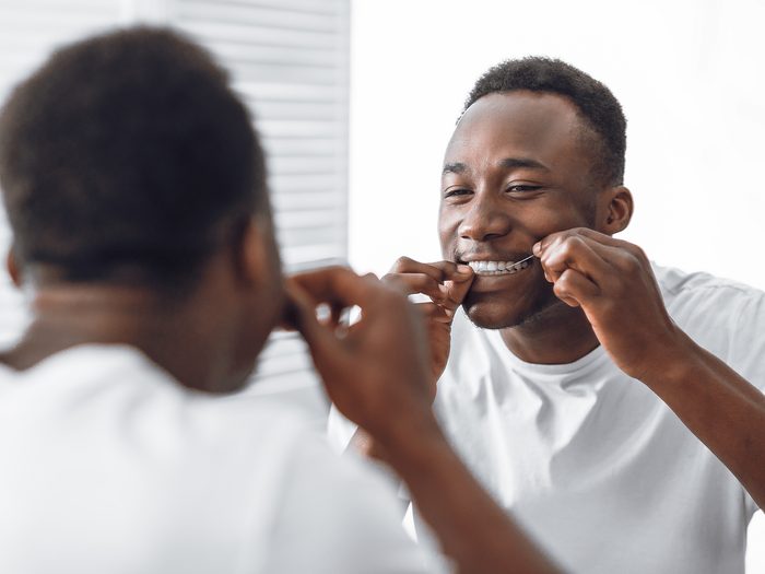 Man flossing his teeth in the mirror