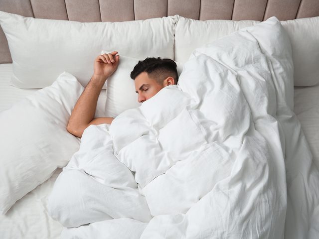 Man sleeping under fluffy white duvet
