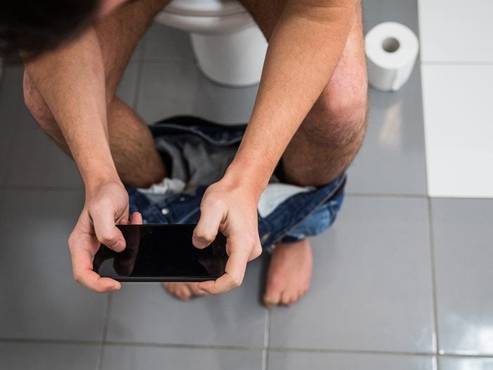 Man using phone on toilet
