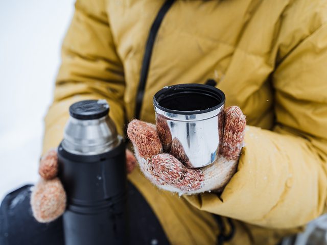 Drinking from thermos vacuum flask in winter