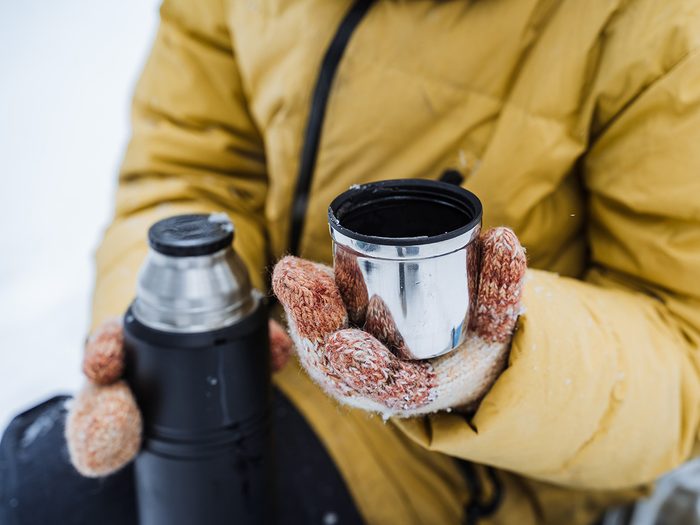 Drinking from thermos vacuum flask in winter
