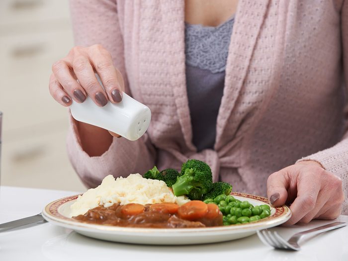 Cooking mistakes - woman adding salt to meal