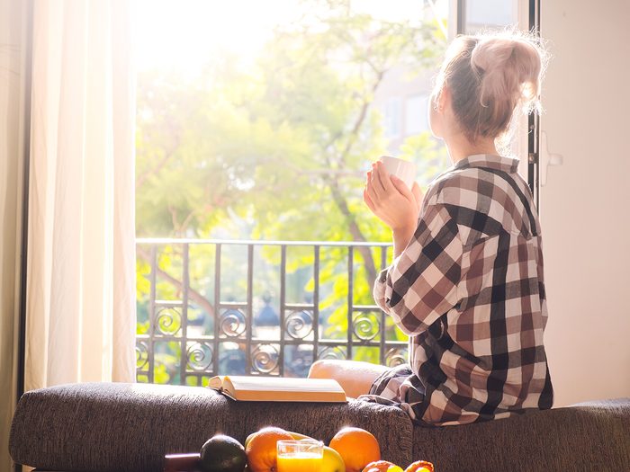 Healthy home checklist - woman enjoying sunshine at open window