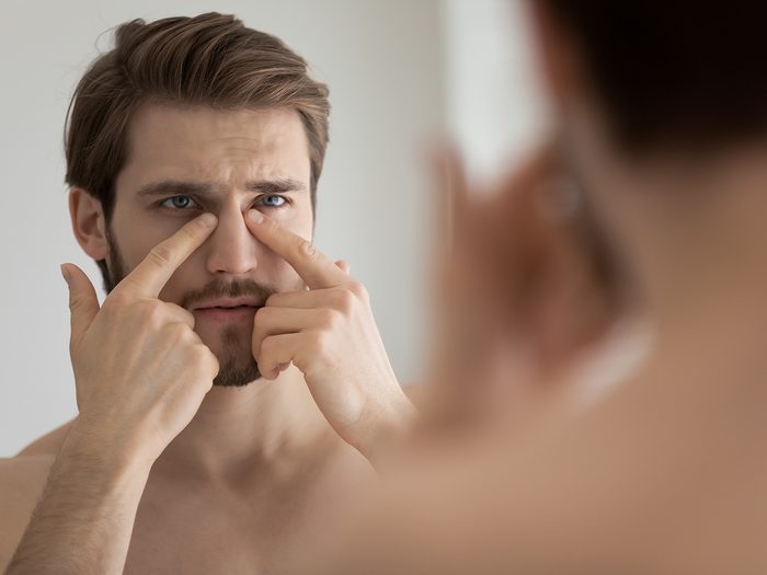 Cancer symptoms - Man examining face in mirror