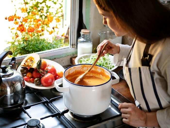 Woman stirring pot on stove