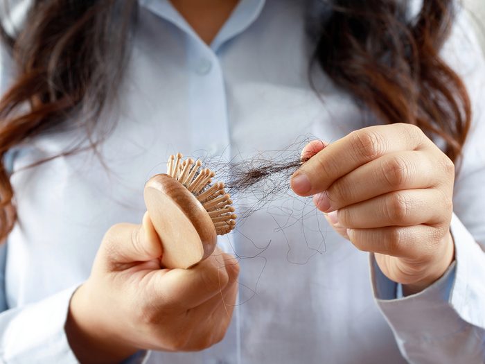 Woman pulling hair out of hairbrush