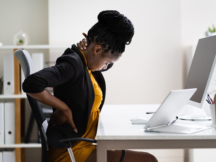 Woman sitting at desk with chronic back pain