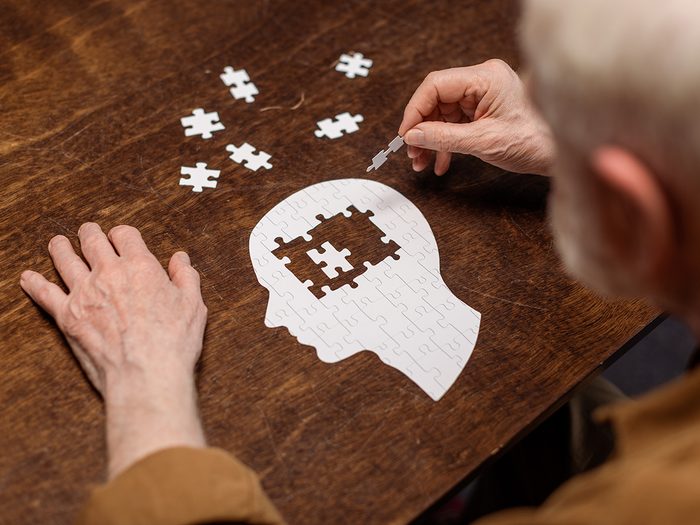 Dementia concept - senior working on jigsaw puzzle