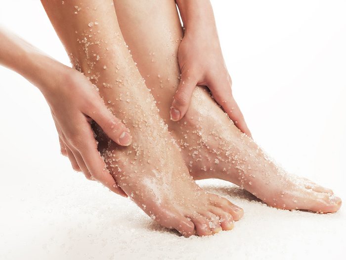 Woman applying salt scrub to feet