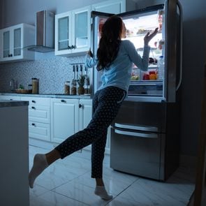 What to eat before bed - a woman looks inside the fridge at night