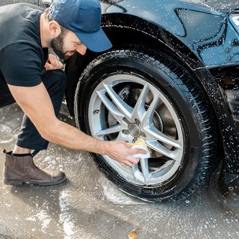 Car washing tips from pros - man washing car tires