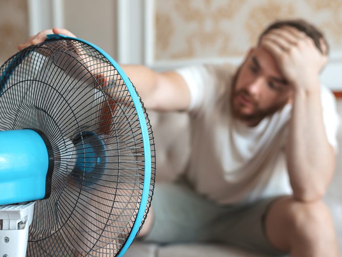 Man with heat stroke sitting in front of fan