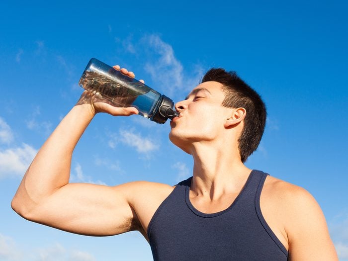 Young man drinking water in summer heat