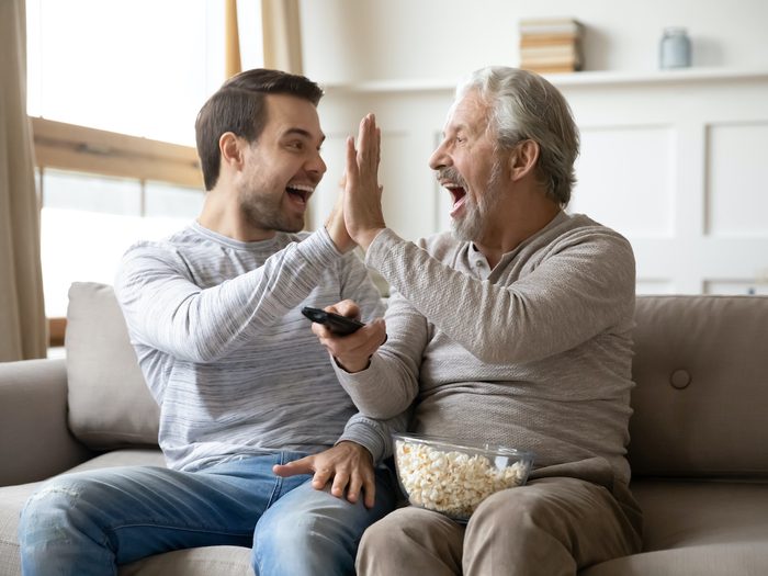 Hockey talk - a younger man and older man giving a high five on couch