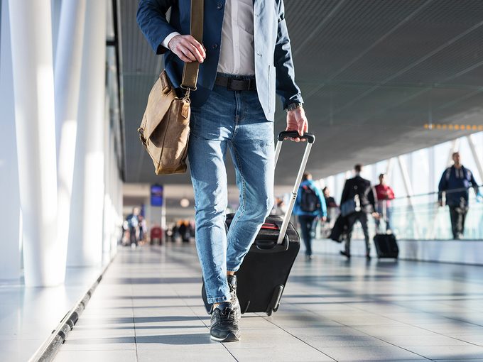 canada budget airline - Man with shoulder bag and hand luggage walking in airport terminal