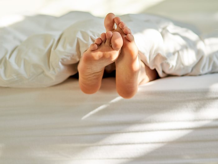 Feet in bed under blankets - summer light