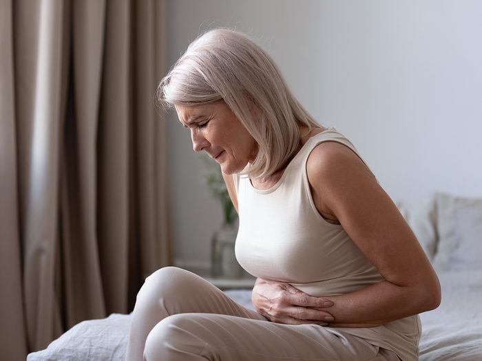 What causes gallstones - woman doubled over with stomach cramps