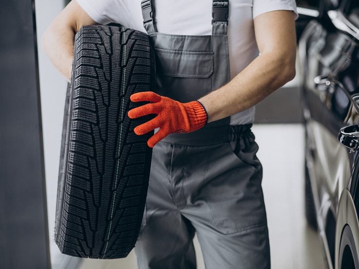 Car mechanic holding tire