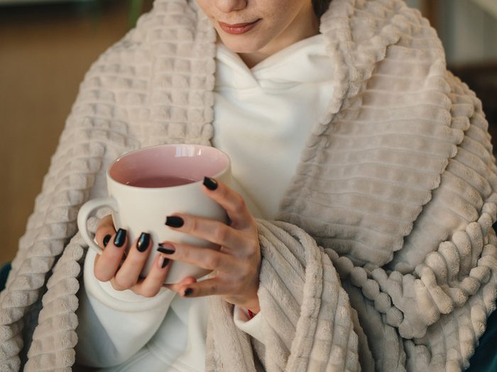Cozy with tea under warm blanket