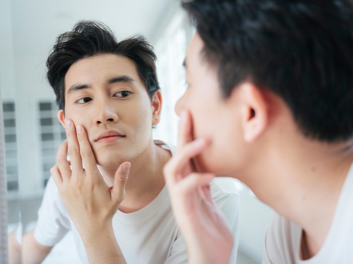 Man examining face in mirror