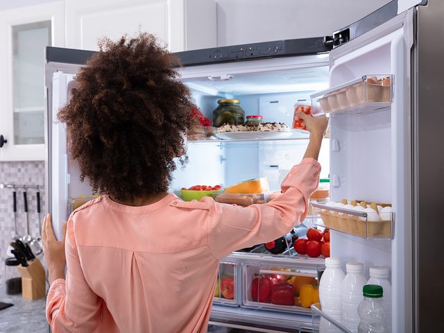 Woman reaching into fridge